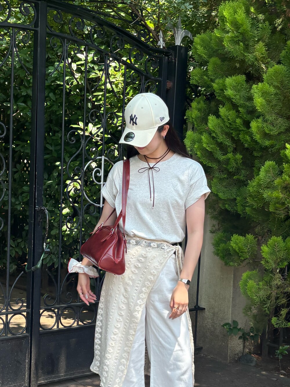 グレー系のTシャツ/カットソー、ホワイト系のデニムパンツ、レッド系のボストンバッグを着用したレディースの夏コーディネートの4枚目の写真