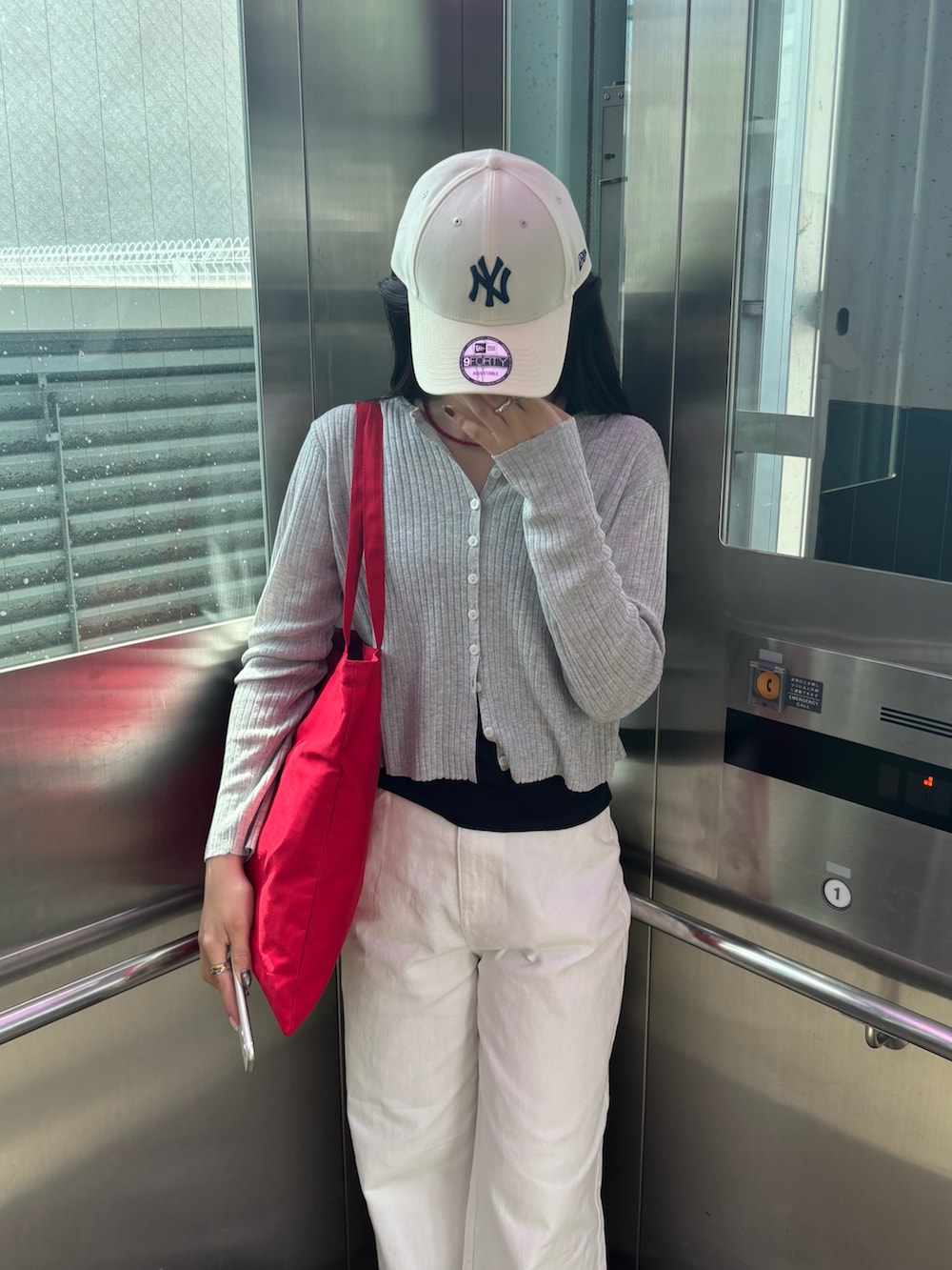 グレー系のカーディガン/ボレロ、レッド系のトートバッグ、ホワイト系のデニムパンツを着用したレディースの春コーディネートの3枚目の写真