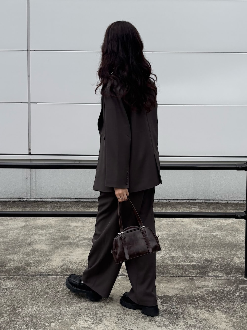 ブラウン系のボストンバッグ、グレー系のテーラードジャケット、グレー系のその他パンツを着用したレディースの春コーディネートの2枚目の写真