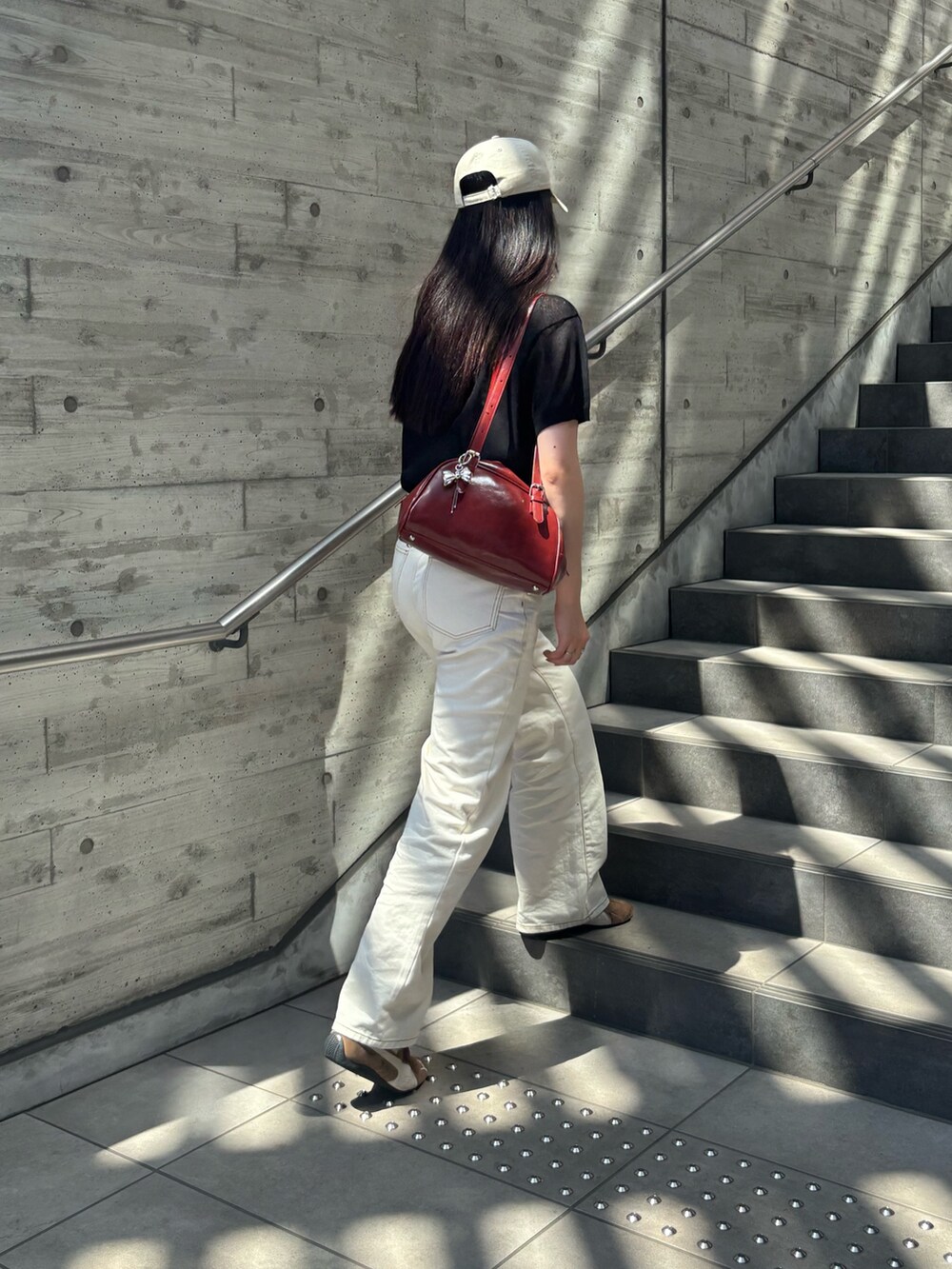 ブラック系のニット/セーター、ホワイト系のデニムパンツ、レッド系のボストンバッグを着用したレディースの夏コーディネートの2枚目の写真