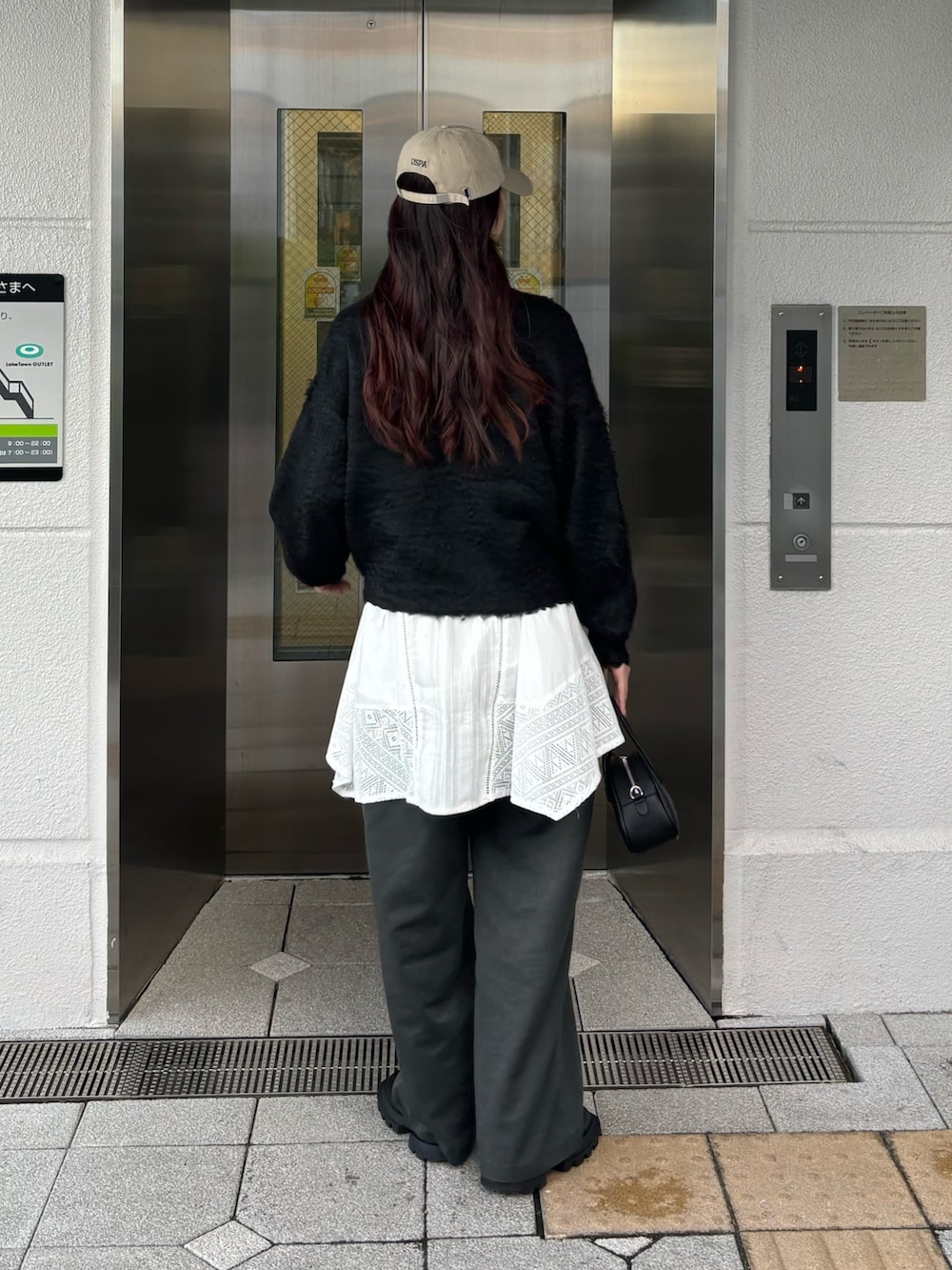 ブラック系のニット/セーター、グレー系のスラックスを着用したレディースの秋コーディネートの3枚目の写真