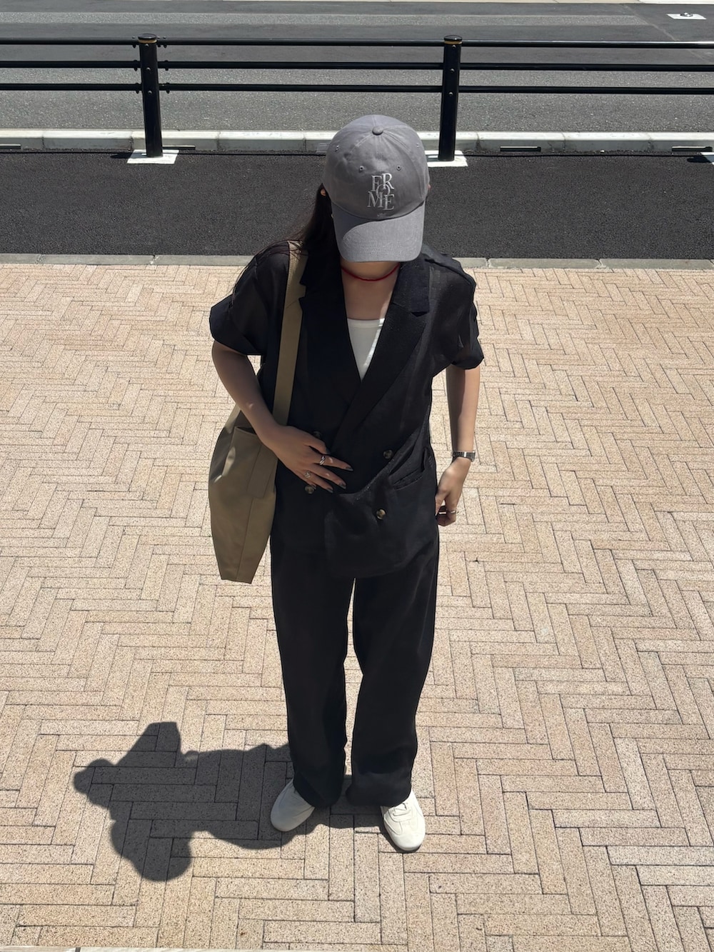 ブラック系のテーラードジャケット、ホワイト系のキャミソール、ブラック系のスラックスを着用したレディースの夏コーディネートの2枚目の写真