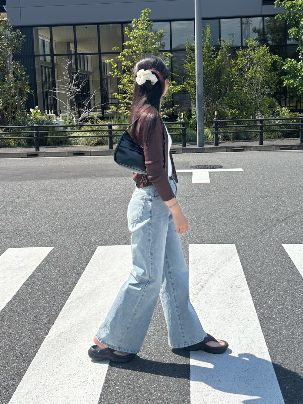 ブルー系のデニムパンツ、ブラック系のハンドバッグ、ブラウン系のカーディガン/ボレロを着用したレディースの夏コーディネートの3枚目の写真