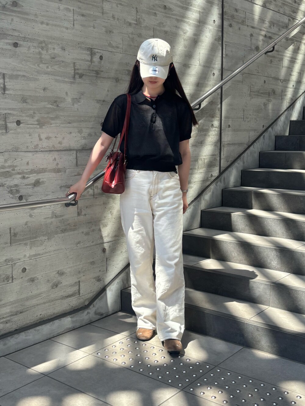 ブラック系のニット/セーター、ホワイト系のデニムパンツ、レッド系のボストンバッグを着用したレディースの夏コーディネートの3枚目の写真