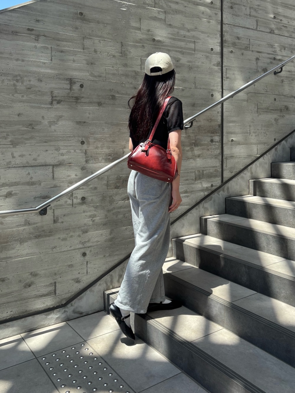 ブラック系のニット/セーター、グレー系のスウェットパンツ、レッド系のボストンバッグを着用したレディースの夏コーディネートの2枚目の写真
