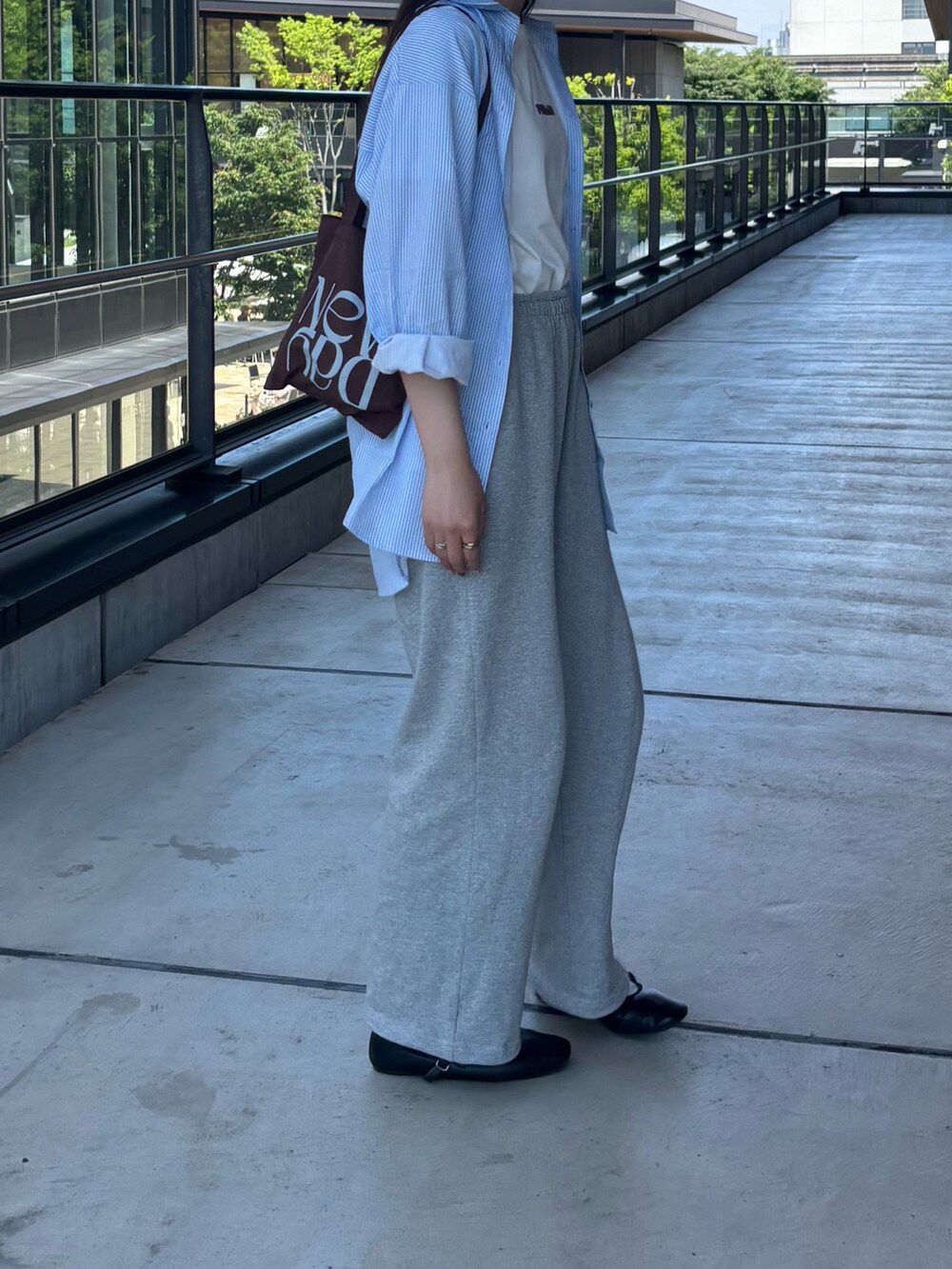 グレー系のスウェットパンツ、ホワイト系のTシャツ/カットソー、ブラウン系のトートバッグを着用したレディースの夏コーディネートの2枚目の写真