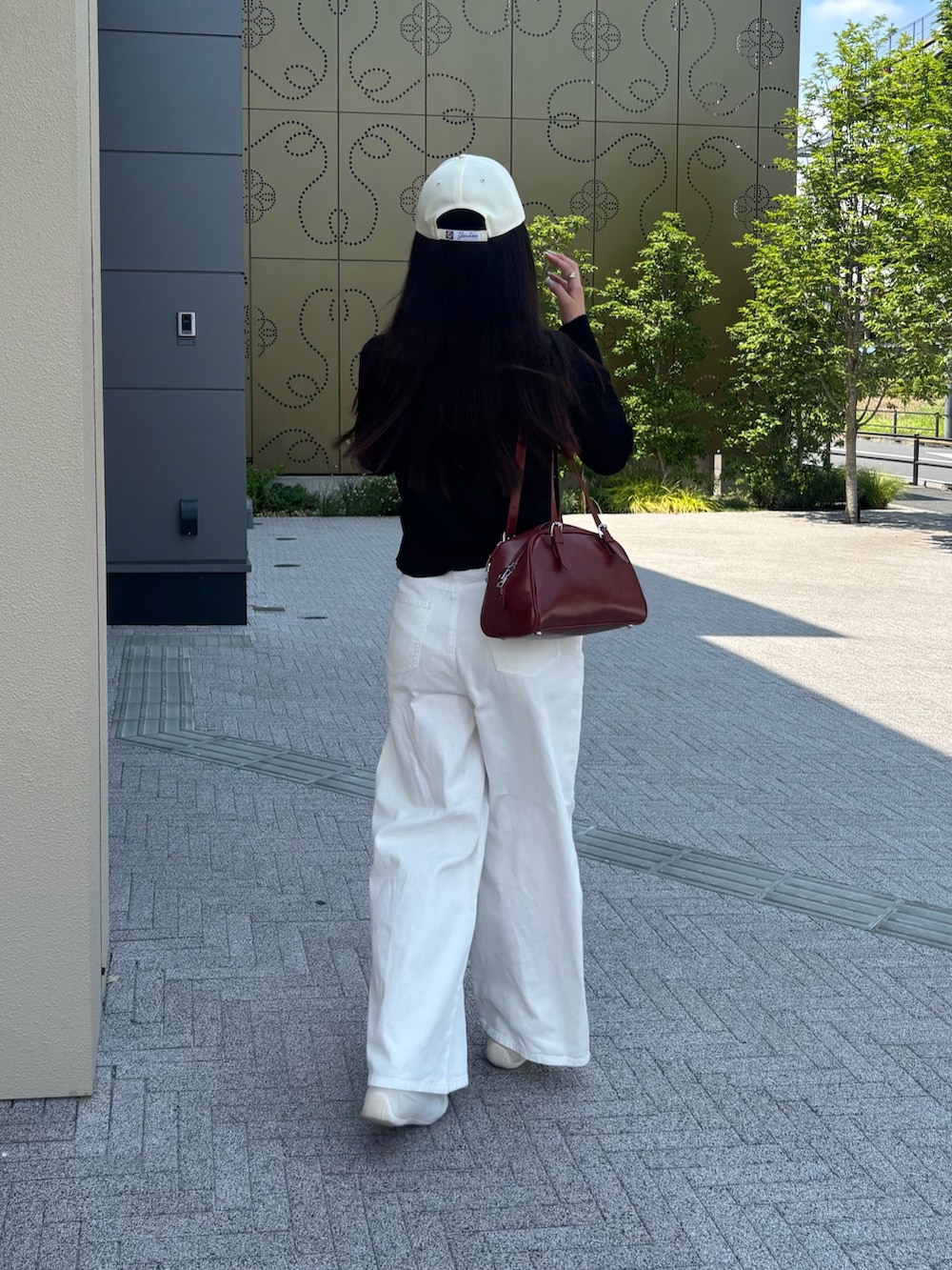 ホワイト系のデニムパンツ、レッド系のボストンバッグ、ブラック系のカーディガン/ボレロを着用したレディースの夏コーディネートの2枚目の写真