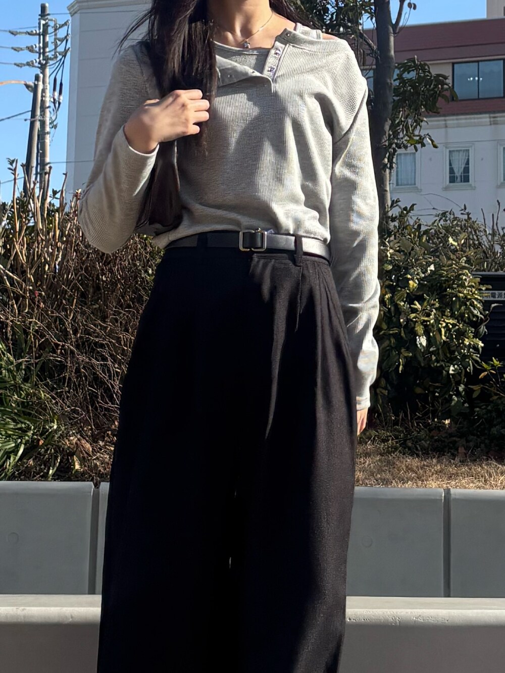 グレー系のTシャツ/カットソー、ブラック系のスラックス、ブラウン系のハンドバッグを着用したレディースの冬コーディネートの2枚目の写真