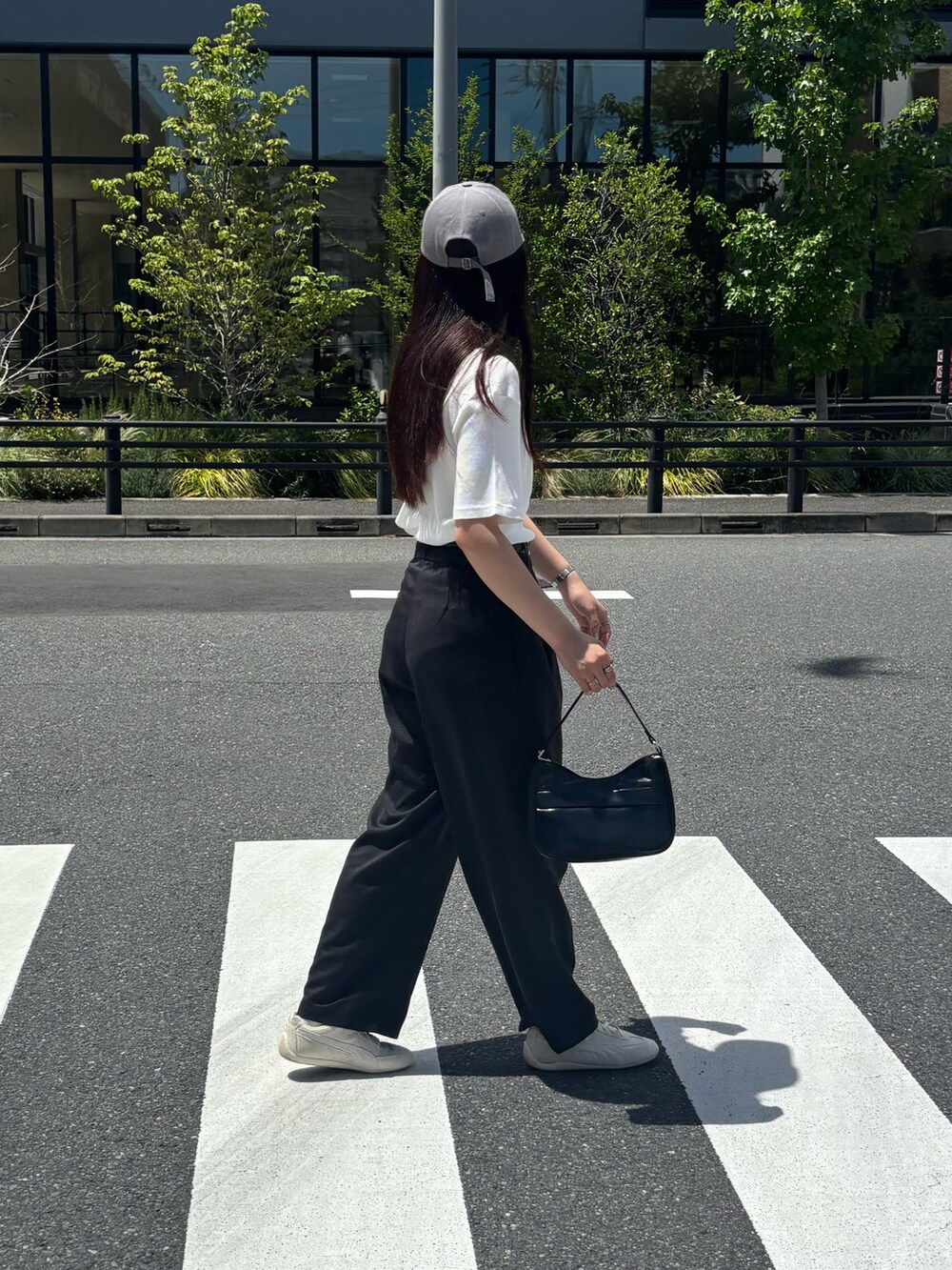 ブラック系のスラックス、ブラック系のハンドバッグ、ホワイト系のTシャツ/カットソーを着用したレディースの夏コーディネートの2枚目の写真