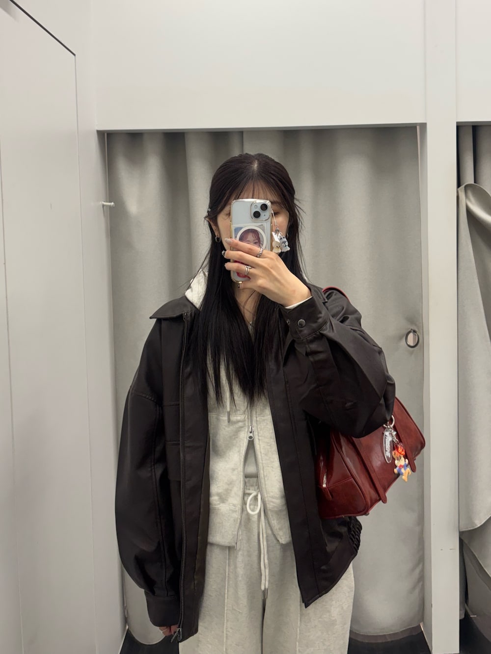 ブラウン系のライダースジャケット、レッド系のボストンバッグ、ホワイト系のスウェットパンツを着用したレディースの冬コーディネートの2枚目の写真