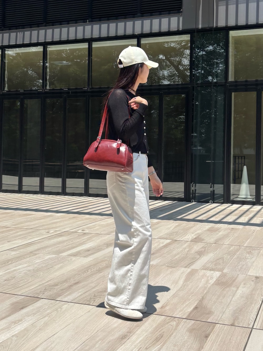 ホワイト系のデニムパンツ、レッド系のボストンバッグ、ブラック系のカーディガン/ボレロを着用したレディースの夏コーディネートの3枚目の写真