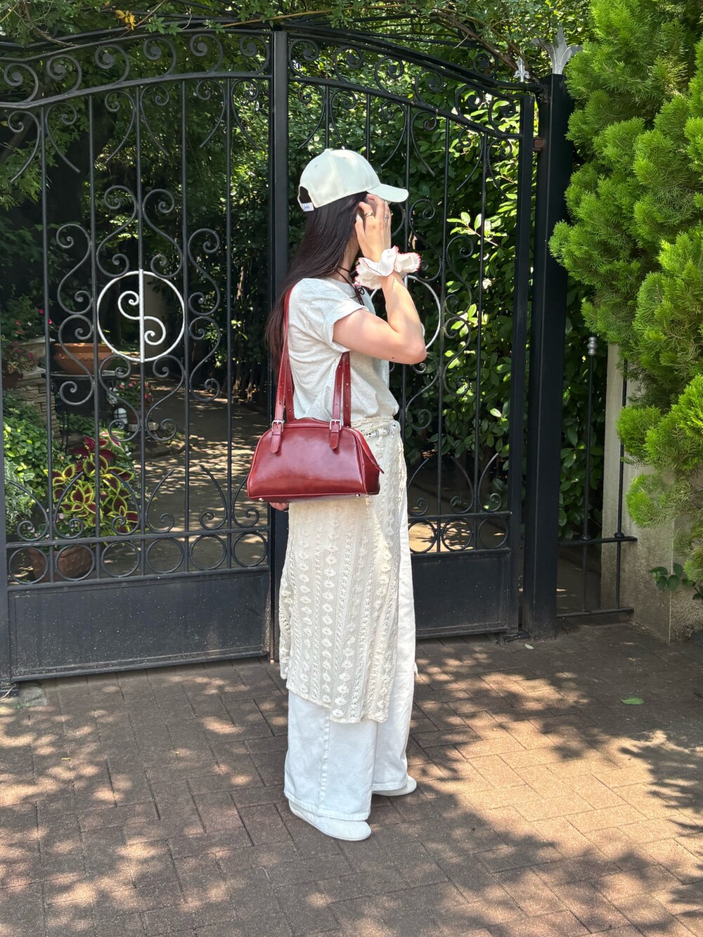 グレー系のTシャツ/カットソー、ホワイト系のデニムパンツ、レッド系のボストンバッグを着用したレディースの夏コーディネートの2枚目の写真