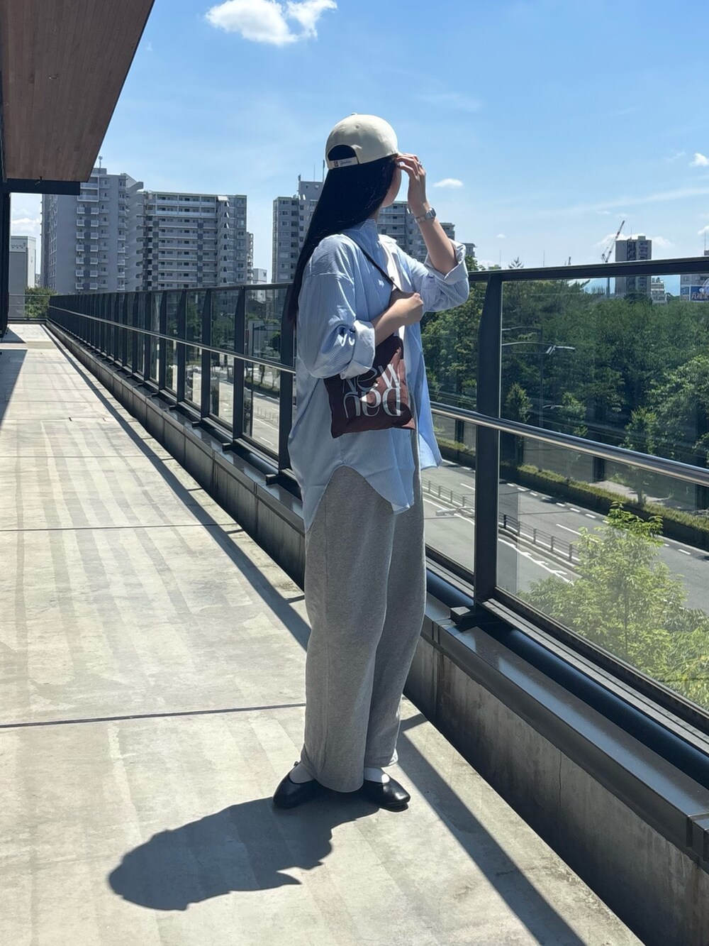 グレー系のスウェットパンツ、ホワイト系のTシャツ/カットソー、ブラウン系のトートバッグを着用したレディースの夏コーディネートの3枚目の写真