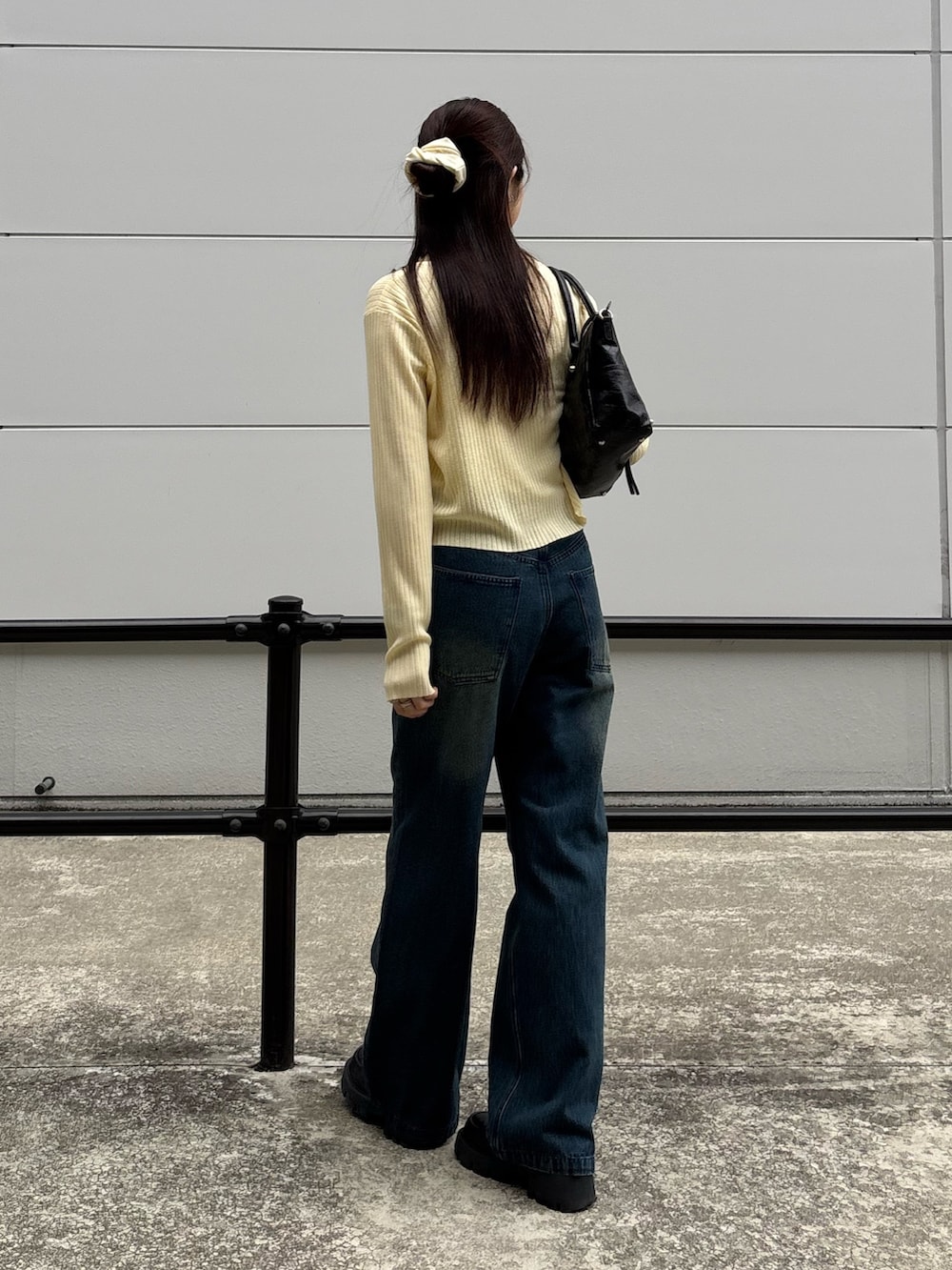 イエロー系のカーディガン/ボレロ、ブルー系のデニムパンツ、ブラック系のショルダーバッグを着用したレディースの春コーディネートの2枚目の写真