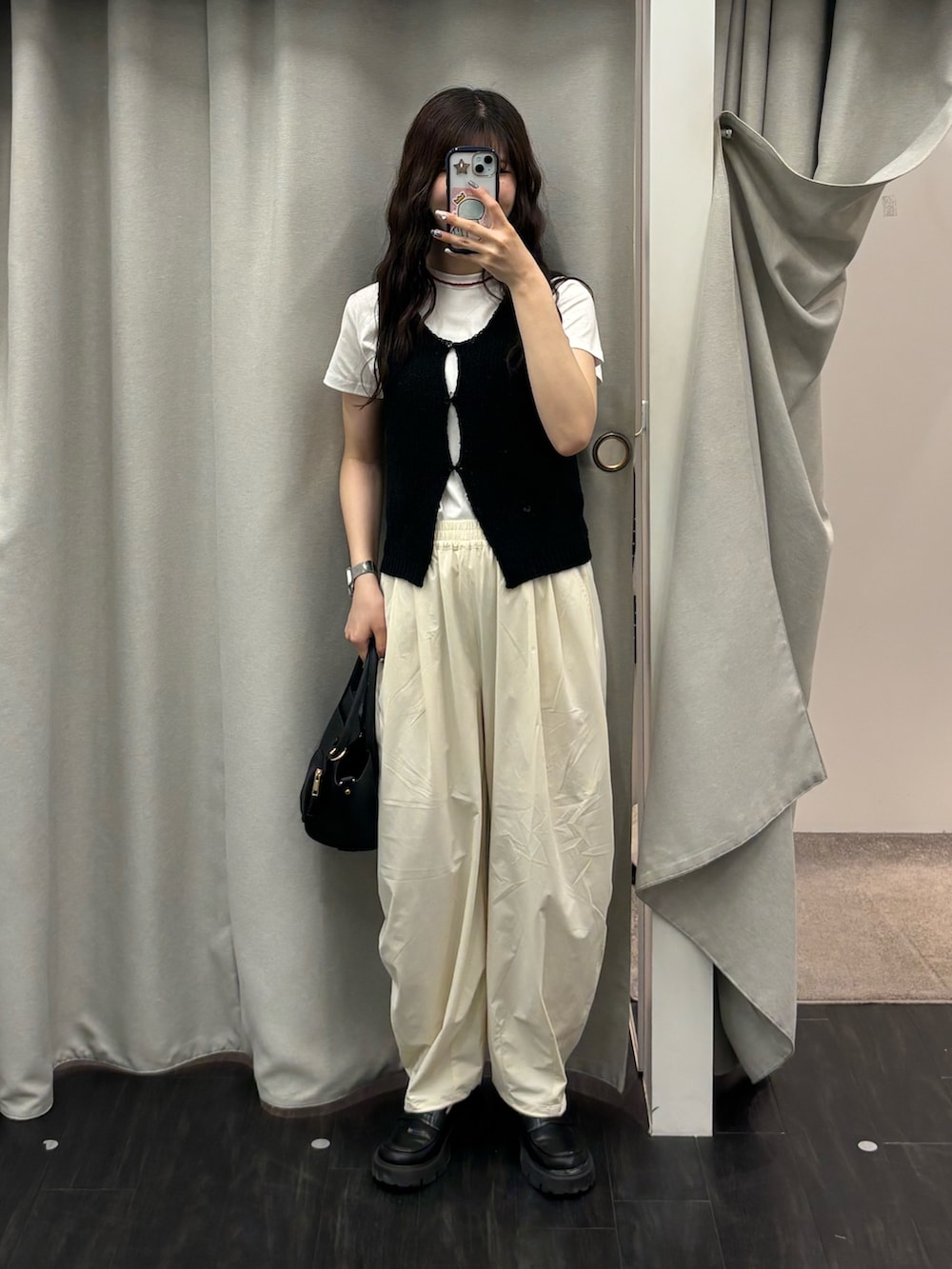 ブラック系のトートバッグ、ホワイト系のその他パンツ、ブラック系のベストを着用したレディースの春コーディネートの2枚目の写真