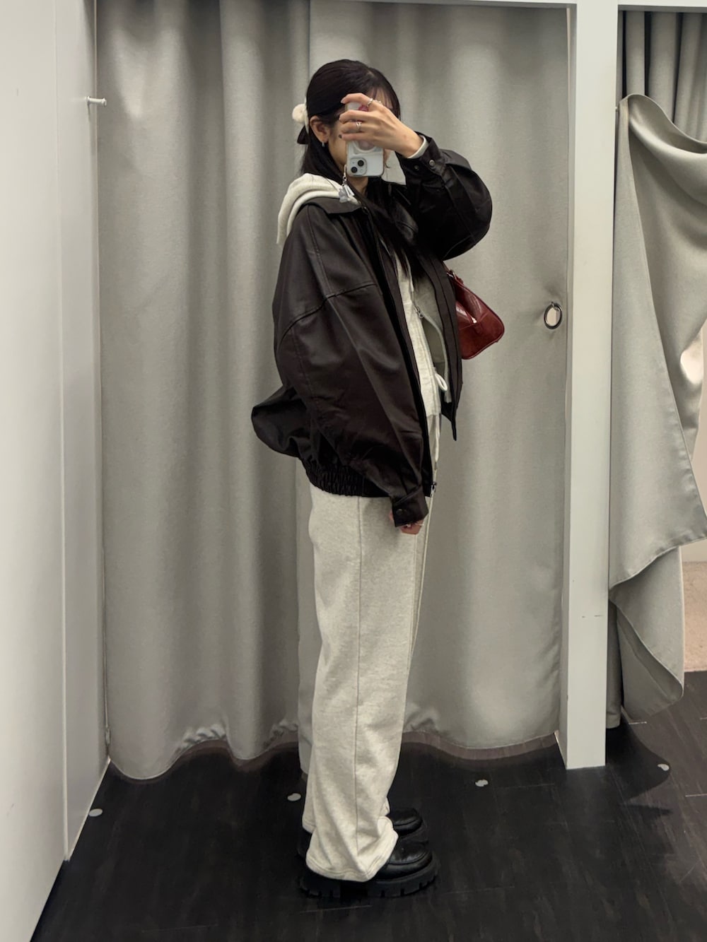 ブラウン系のライダースジャケット、レッド系のボストンバッグ、ホワイト系のスウェットパンツを着用したレディースの冬コーディネートの3枚目の写真