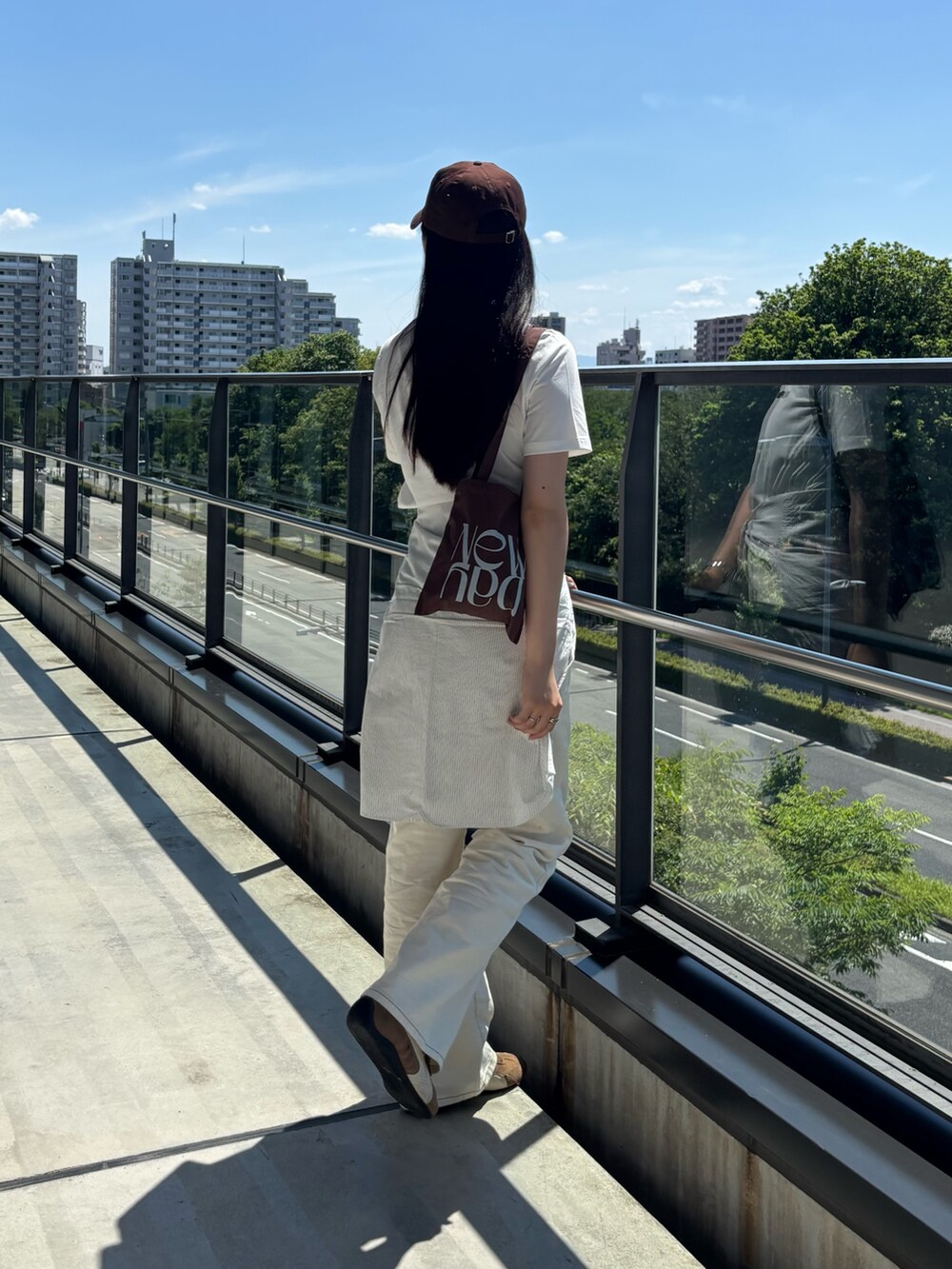 ホワイト系のTシャツ/カットソー、ブラウン系のトートバッグ、ホワイト系のデニムパンツを着用したレディースの夏コーディネートの2枚目の写真