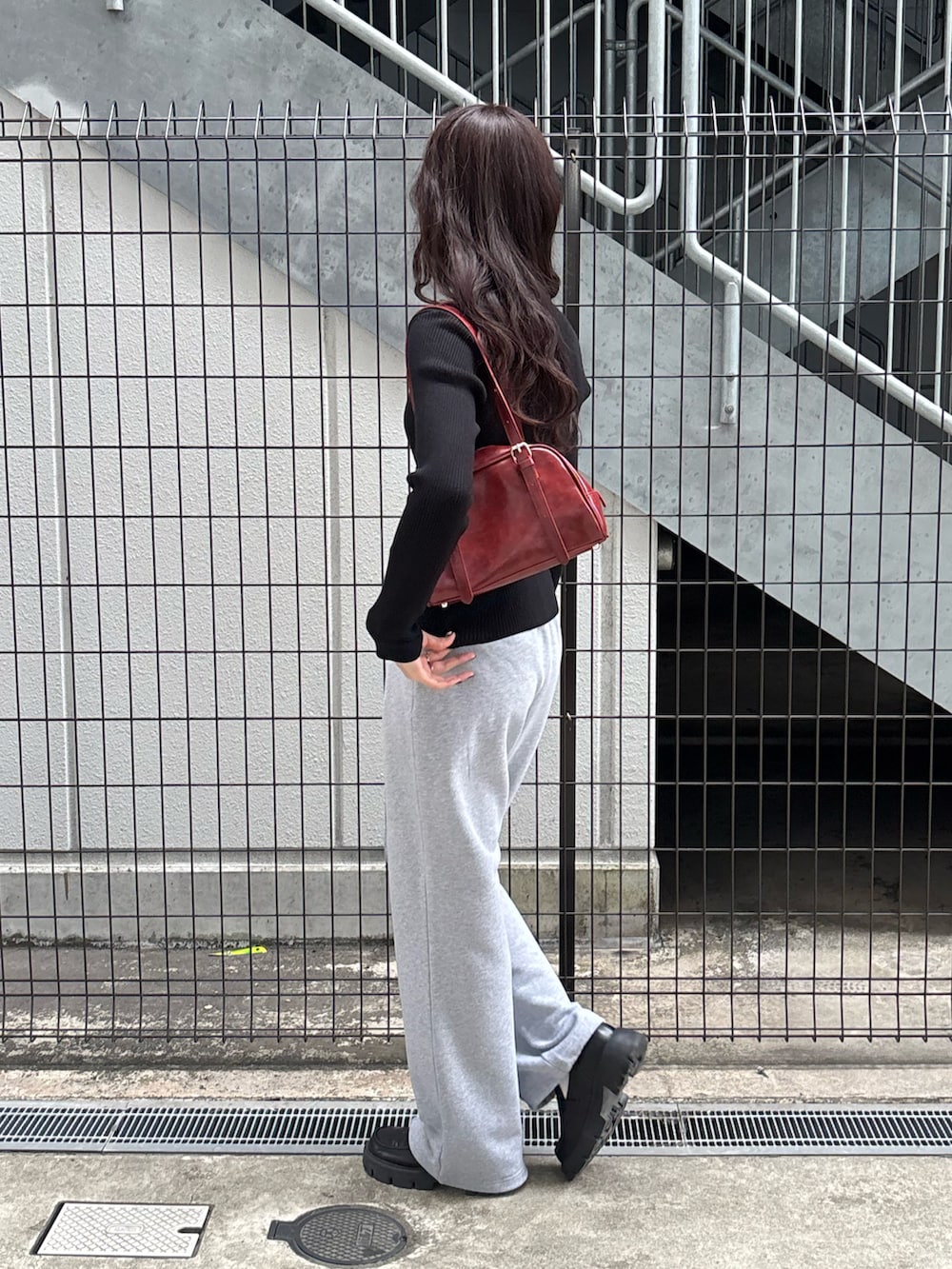 レッド系のボストンバッグ、グレー系のスウェットパンツ、ブラック系のカーディガン/ボレロを着用したレディースの春コーディネートの3枚目の写真