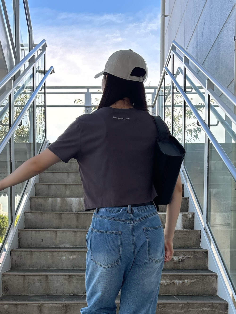 グレー系のTシャツ/カットソー、ブルー系のデニムパンツを着用したレディースの夏コーディネートの4枚目の写真