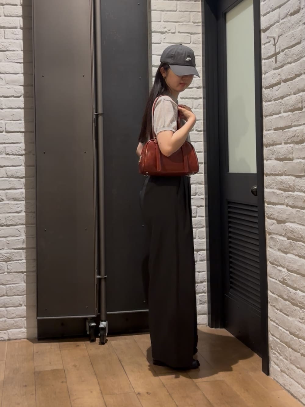 グレー系のニット/セーター、レッド系のボストンバッグ、ブラック系のその他パンツを着用したレディースの夏コーディネートの2枚目の写真