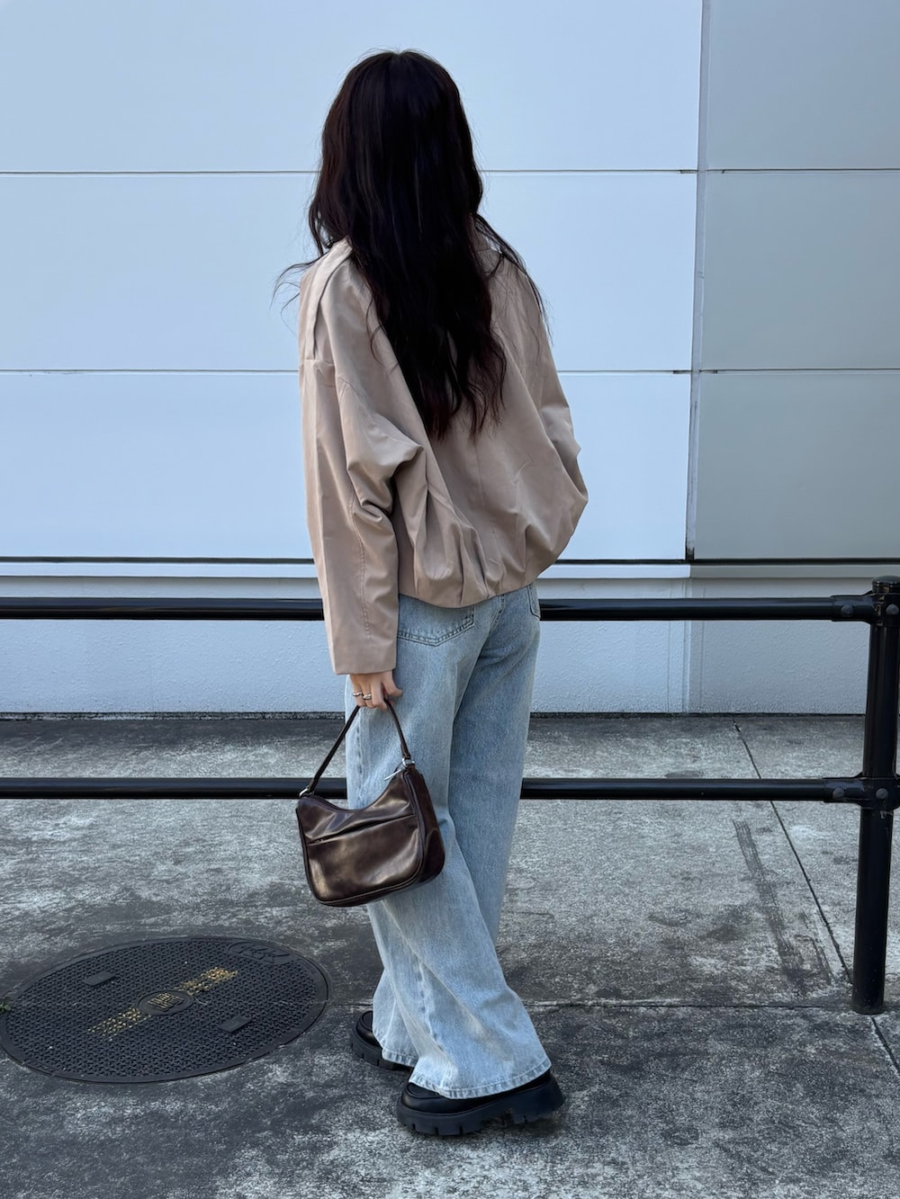 ベージュ系のブルゾン、ブラウン系のハンドバッグ、ブルー系のデニムパンツを着用したレディースの春コーディネートの3枚目の写真