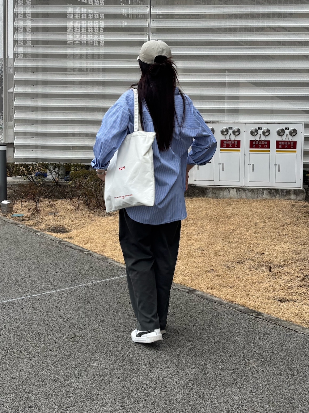 ブルー系のシャツ/ブラウス、ホワイト系のトートバッグ、グレー系のスラックスを着用したレディースの春コーディネートの3枚目の写真