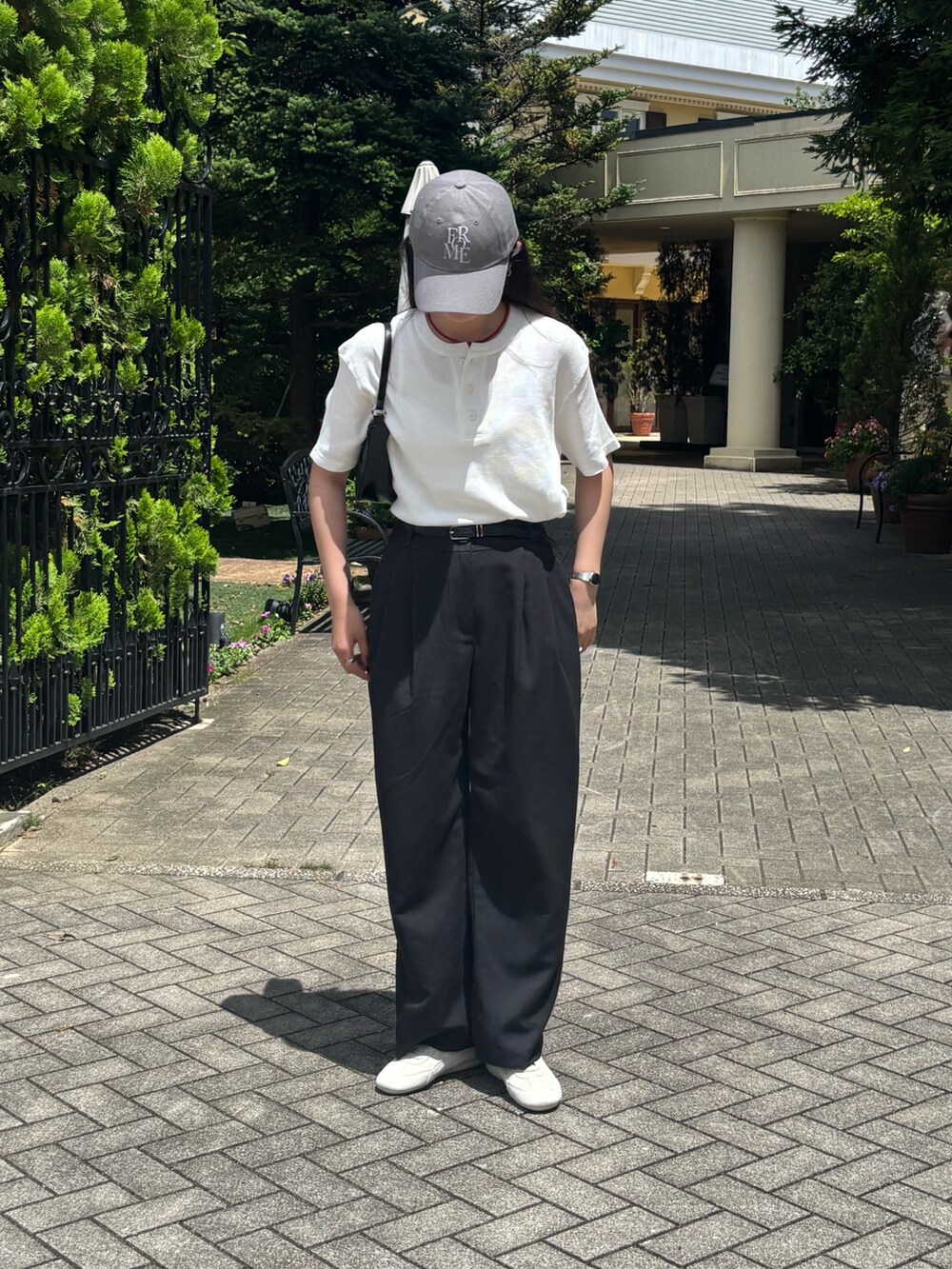 ブラック系のスラックス、ブラック系のハンドバッグ、ホワイト系のTシャツ/カットソーを着用したレディースの夏コーディネートの3枚目の写真