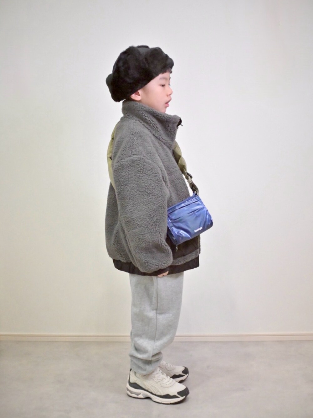 グレー系のスウェットパンツ、グレー系のブルゾン、ブルー系のショルダーバッグを着用したキッズの冬コーディネートの4枚目の写真