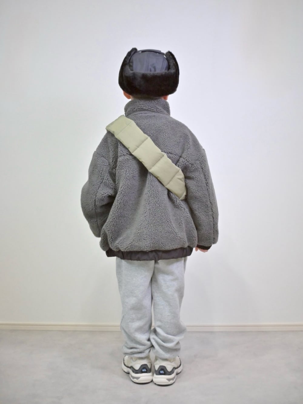 グレー系のスウェットパンツ、グレー系のブルゾン、ブルー系のショルダーバッグを着用したキッズの冬コーディネートの3枚目の写真