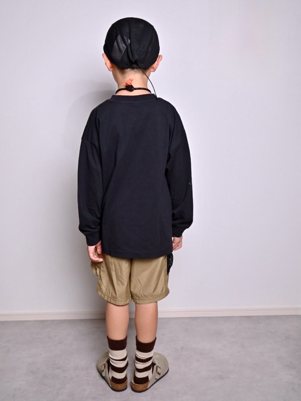 ブラック系のTシャツ/カットソー、ベージュ系のサンダル、グリーン系のその他パンツを着用したキッズの秋コーディネートの3枚目の写真