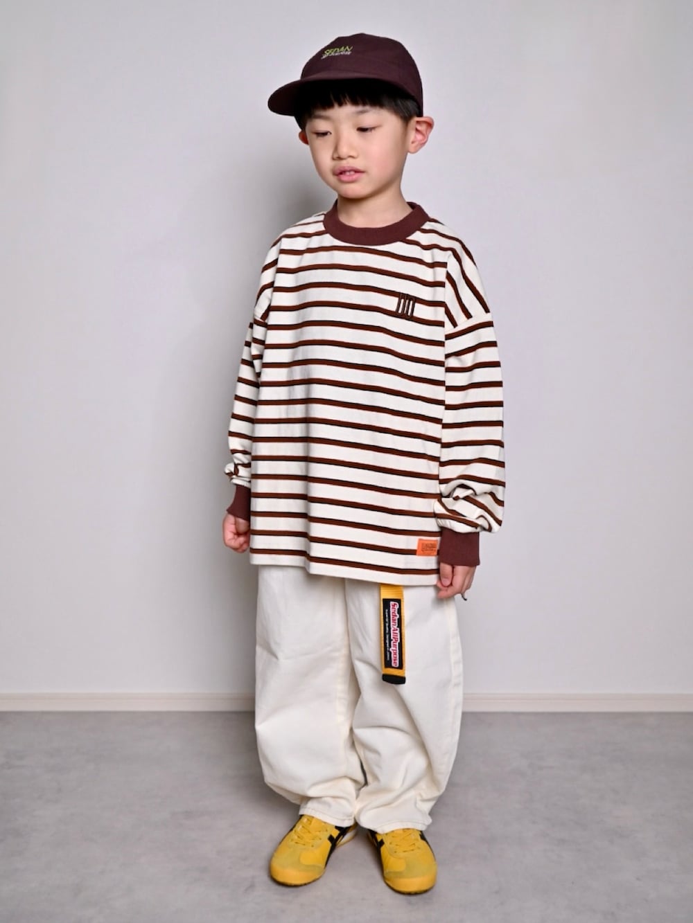 ホワイト系のTシャツ/カットソー、イエロー系のスニーカー、イエロー系のベルトを着用したキッズの春コーディネートの2枚目の写真