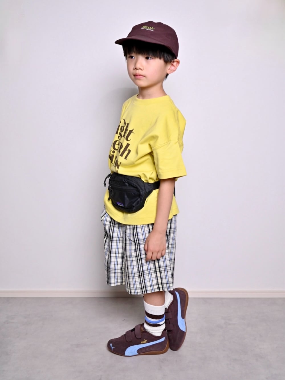 イエロー系のTシャツ/カットソー、ホワイト系のチノパンツ、ブラウン系のスニーカーを着用したキッズの春コーディネートの4枚目の写真