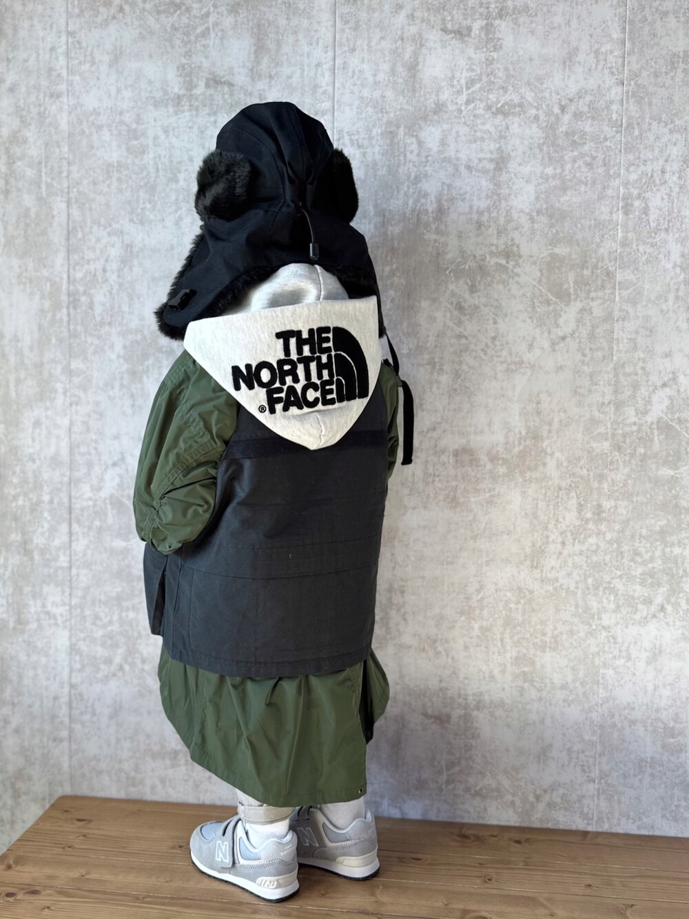 ホワイト系のパーカー、グリーン系のモッズコート、ブラック系のベストを着用したキッズの冬コーディネートの2枚目の写真