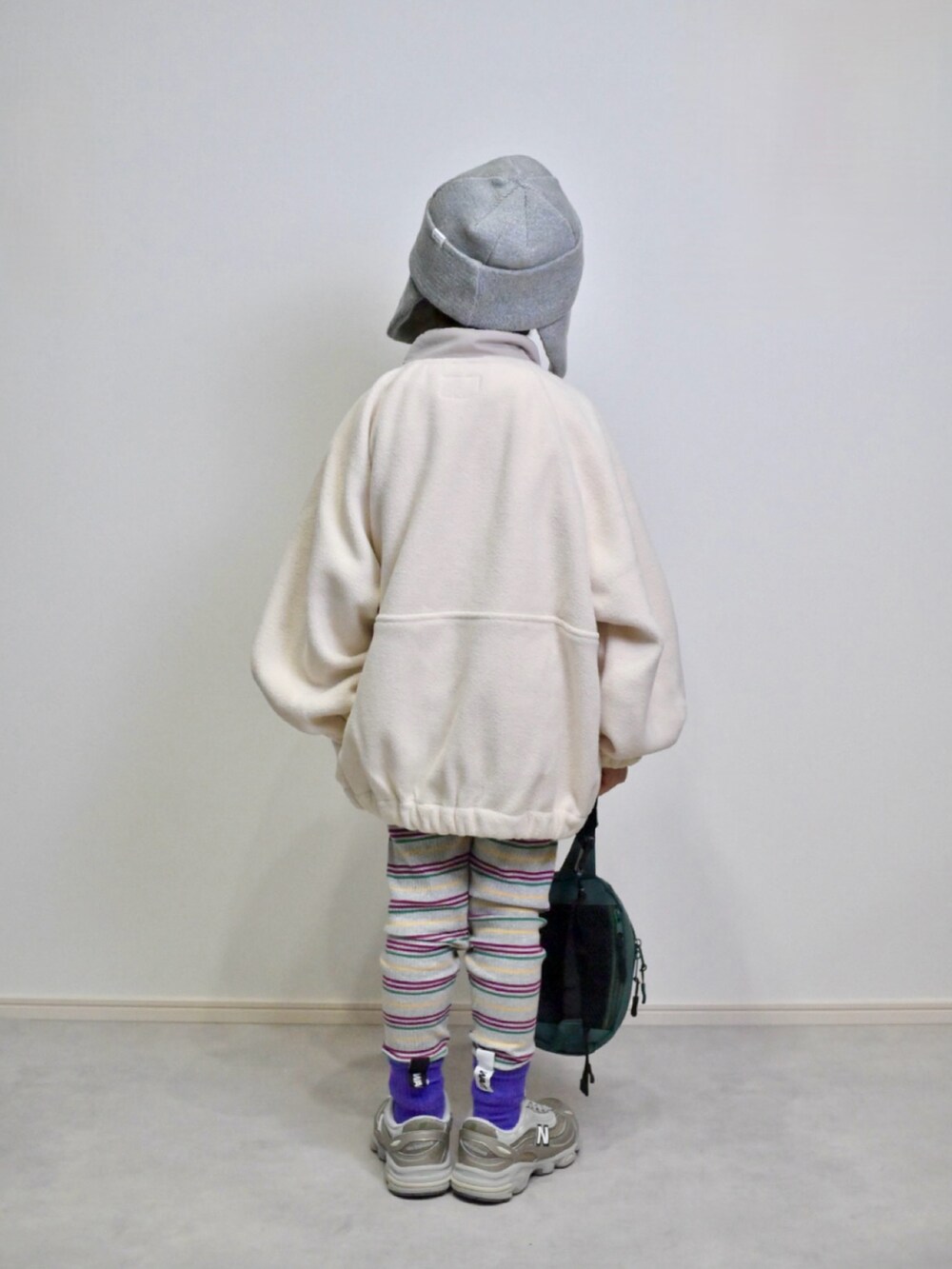 ベージュ系のスニーカー、グリーン系のボディバッグ/ウエストポーチ、ホワイト系のブルゾンを着用したキッズの秋コーディネートの3枚目の写真