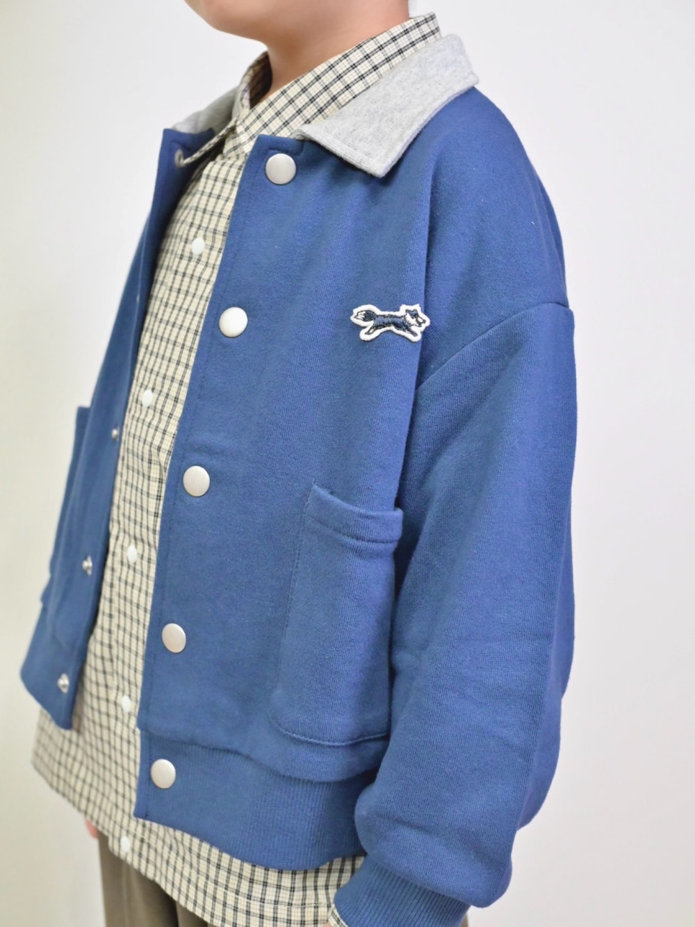 ブルー系のカーディガン/ボレロ、ホワイト系のシャツ/ブラウス、ブラウン系のスラックスを着用したキッズの秋コーディネートの2枚目の写真