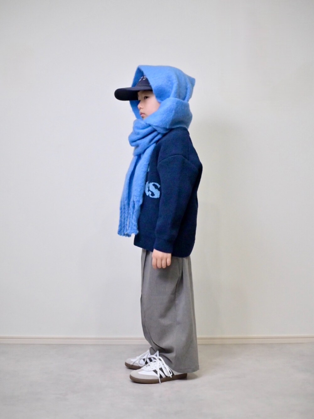 ブルー系のニット/セーター、グレー系のスラックス、ホワイト系のスニーカーを着用したキッズの冬コーディネートの2枚目の写真