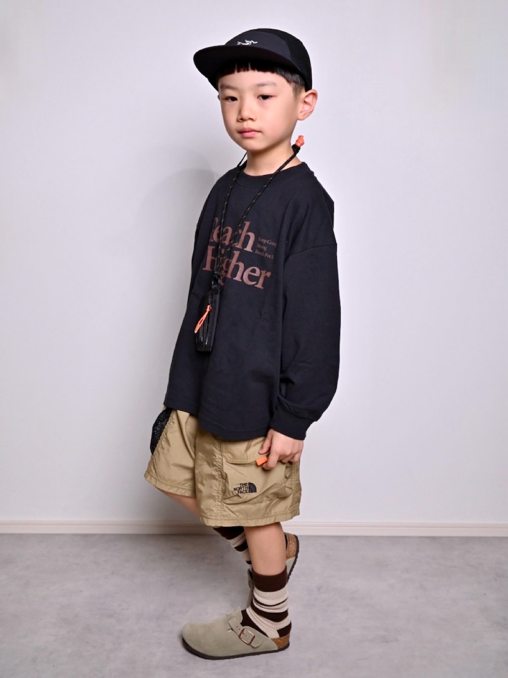 ブラック系のTシャツ/カットソー、ベージュ系のサンダル、グリーン系のその他パンツを着用したキッズの秋コーディネートの2枚目の写真