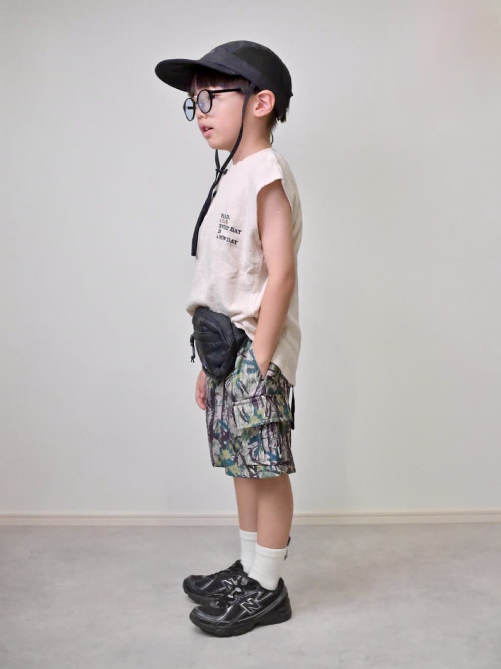 ベージュ系のカーゴパンツ、ホワイト系のTシャツ/カットソー、ブラック系のボディバッグ/ウエストポーチを着用したキッズの夏コーディネートの2枚目の写真