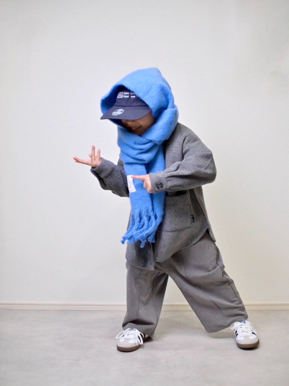 ブルー系のニット/セーター、グレー系のスラックス、ホワイト系のスニーカーを着用したキッズの冬コーディネートの5枚目の写真