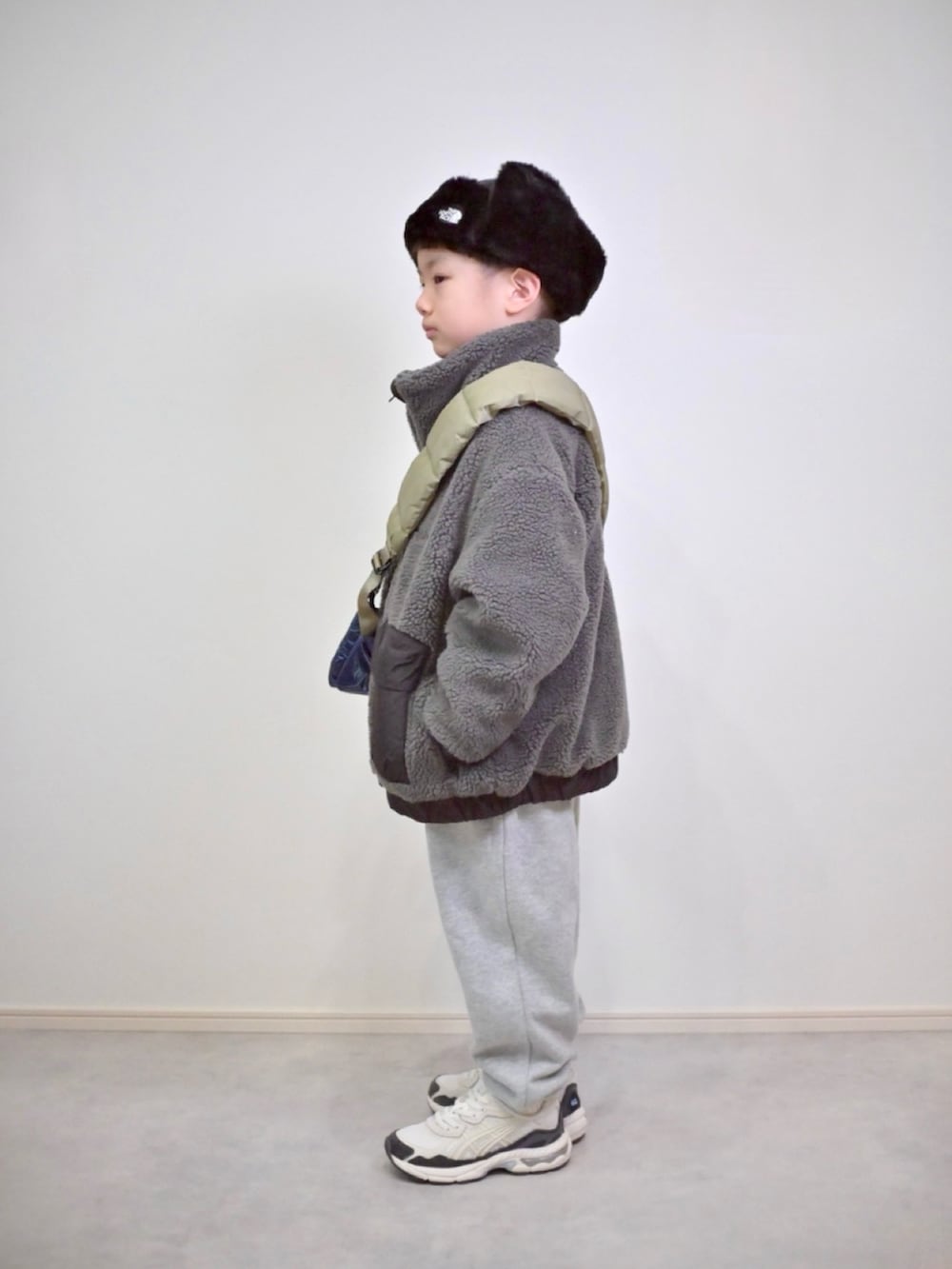 グレー系のスウェットパンツ、グレー系のブルゾン、ブルー系のショルダーバッグを着用したキッズの冬コーディネートの2枚目の写真