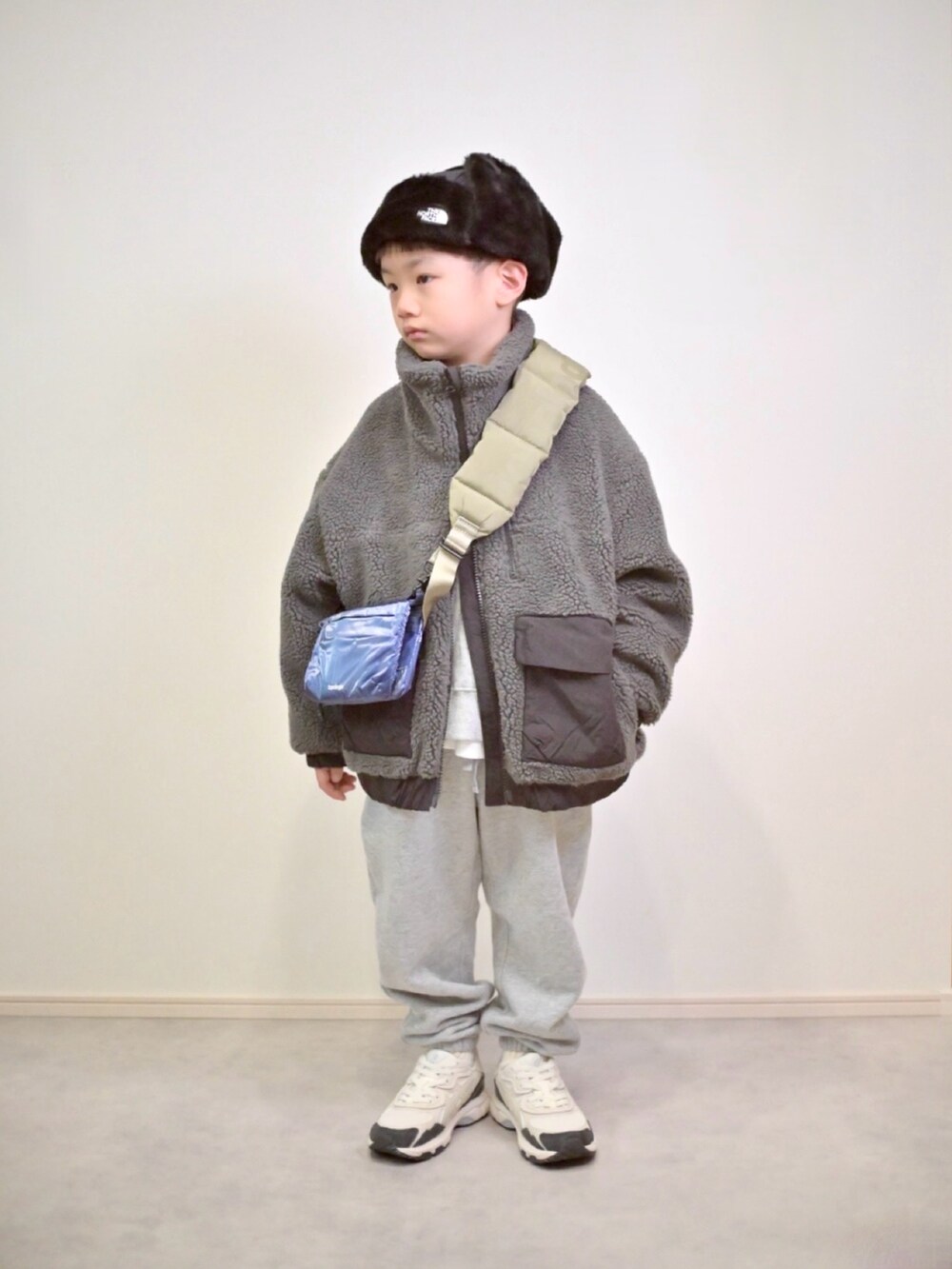 グレー系のスウェットパンツ、グレー系のブルゾン、ブルー系のショルダーバッグを着用したキッズの冬コーディネートの5枚目の写真