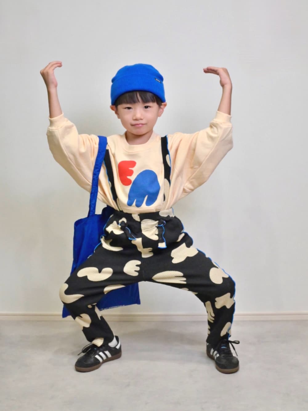 ブルー系のトートバッグ、ブラック系のスニーカー、ホワイト系のスウェットを着用したキッズの秋コーディネートの4枚目の写真