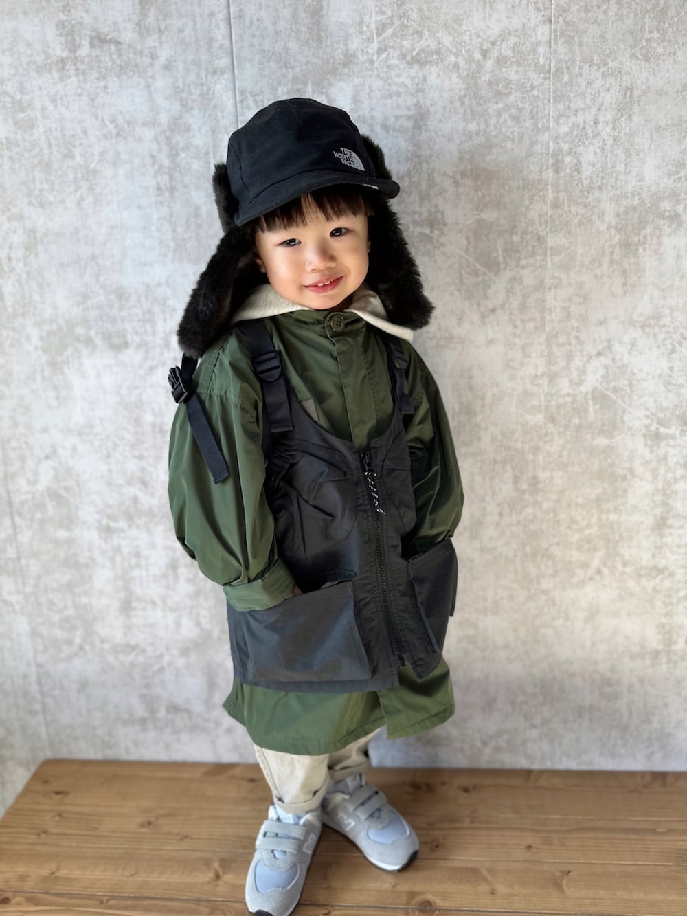 ホワイト系のパーカー、グリーン系のモッズコート、ブラック系のベストを着用したキッズの冬コーディネートの3枚目の写真