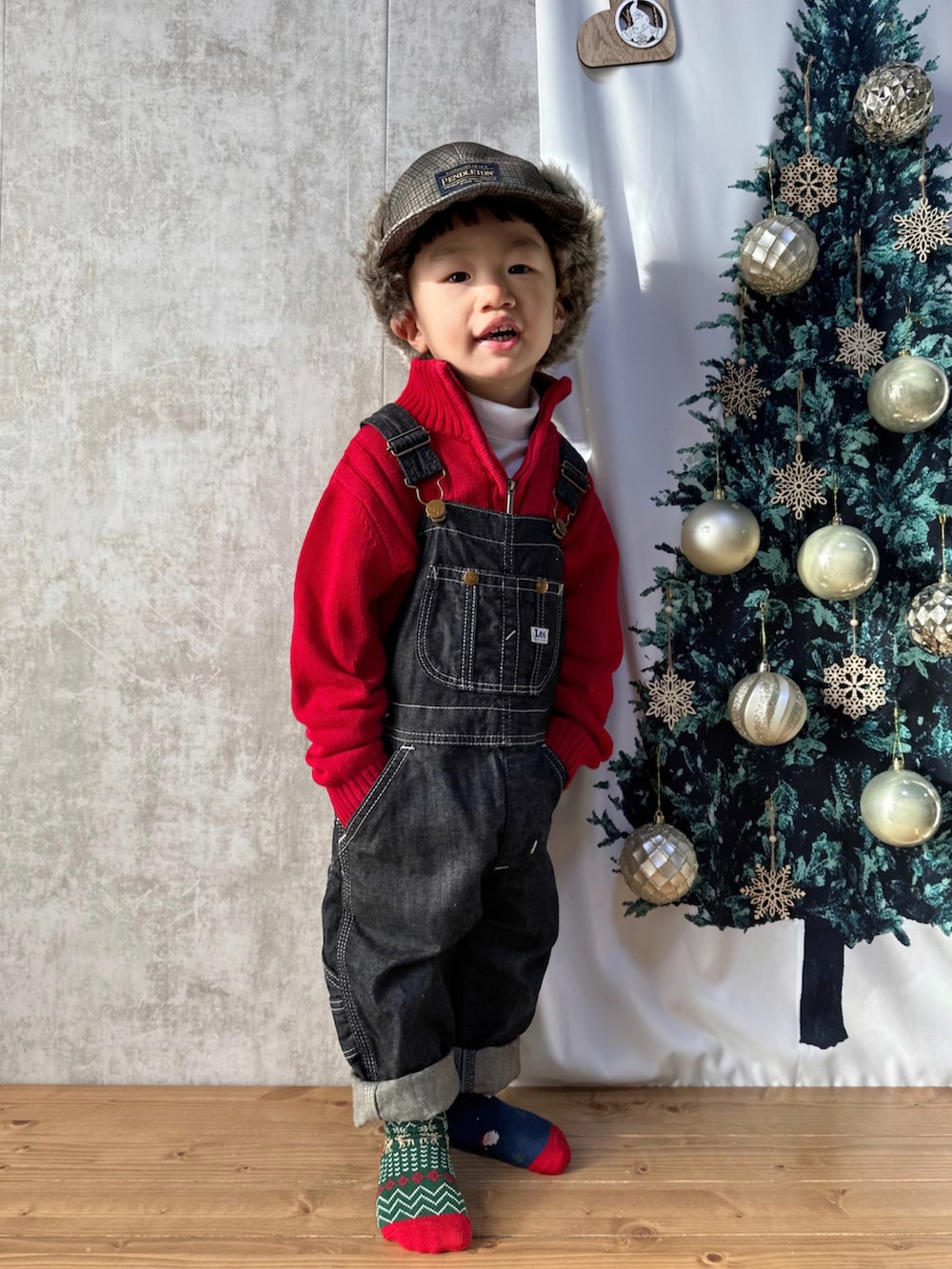 レッド系のニット/セーター、ホワイト系のトップス、ブルー系のサロペット/オーバーオールを着用したキッズの冬コーディネートの3枚目の写真