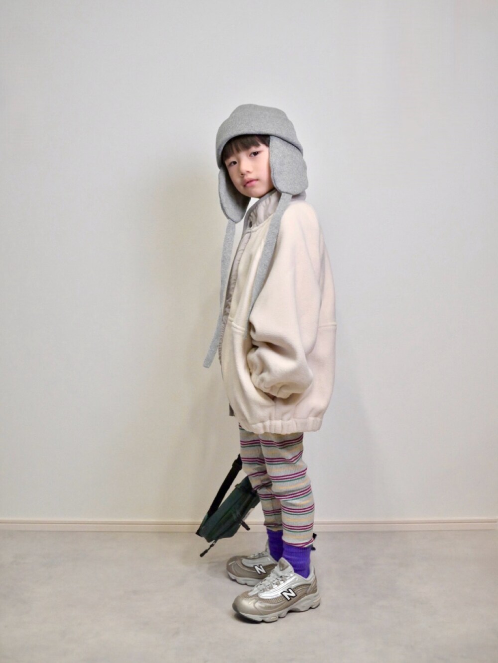 ベージュ系のスニーカー、グリーン系のボディバッグ/ウエストポーチ、ホワイト系のブルゾンを着用したキッズの秋コーディネートの2枚目の写真