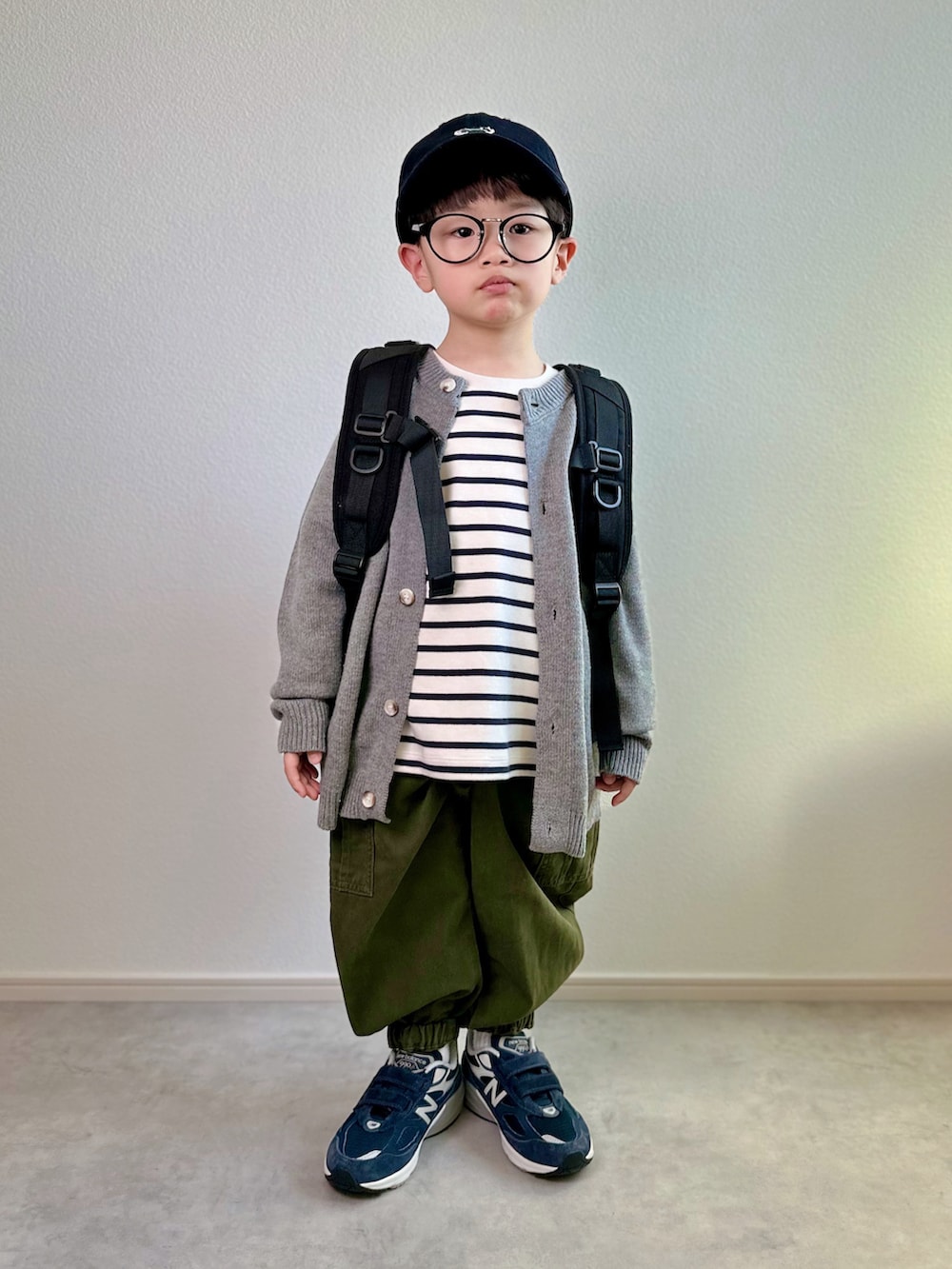 グレー系のカーディガン/ボレロ、ホワイト系のTシャツ/カットソー、グリーン系のカーゴパンツを着用したキッズの冬コーディネートの2枚目の写真