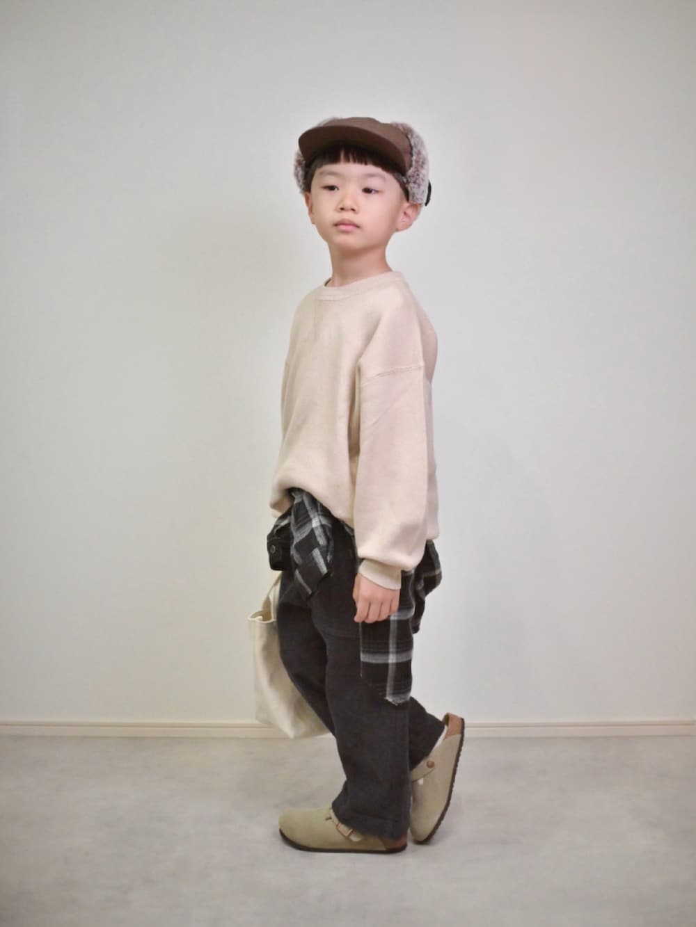 ベージュ系のニット/セーター、ブラック系のシャツ/ブラウス、グレー系のチノパンツを着用したキッズの秋コーディネートの3枚目の写真