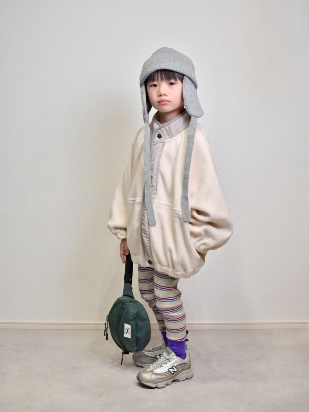 ベージュ系のスニーカー、グリーン系のボディバッグ/ウエストポーチ、ホワイト系のブルゾンを着用したキッズの秋コーディネートの4枚目の写真