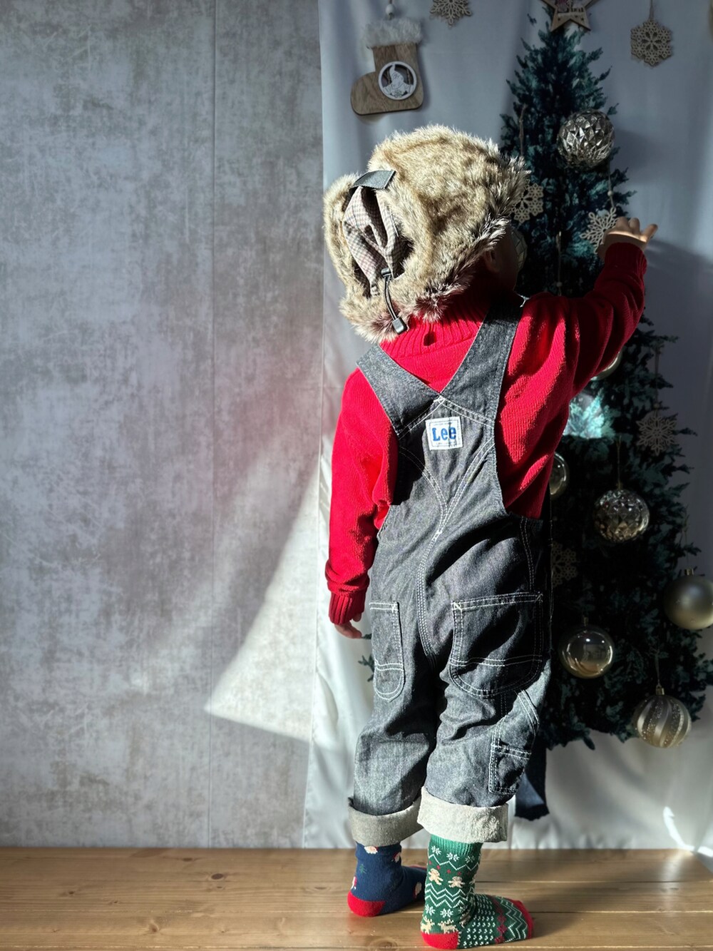 レッド系のニット/セーター、ホワイト系のトップス、ブルー系のサロペット/オーバーオールを着用したキッズの冬コーディネートの5枚目の写真