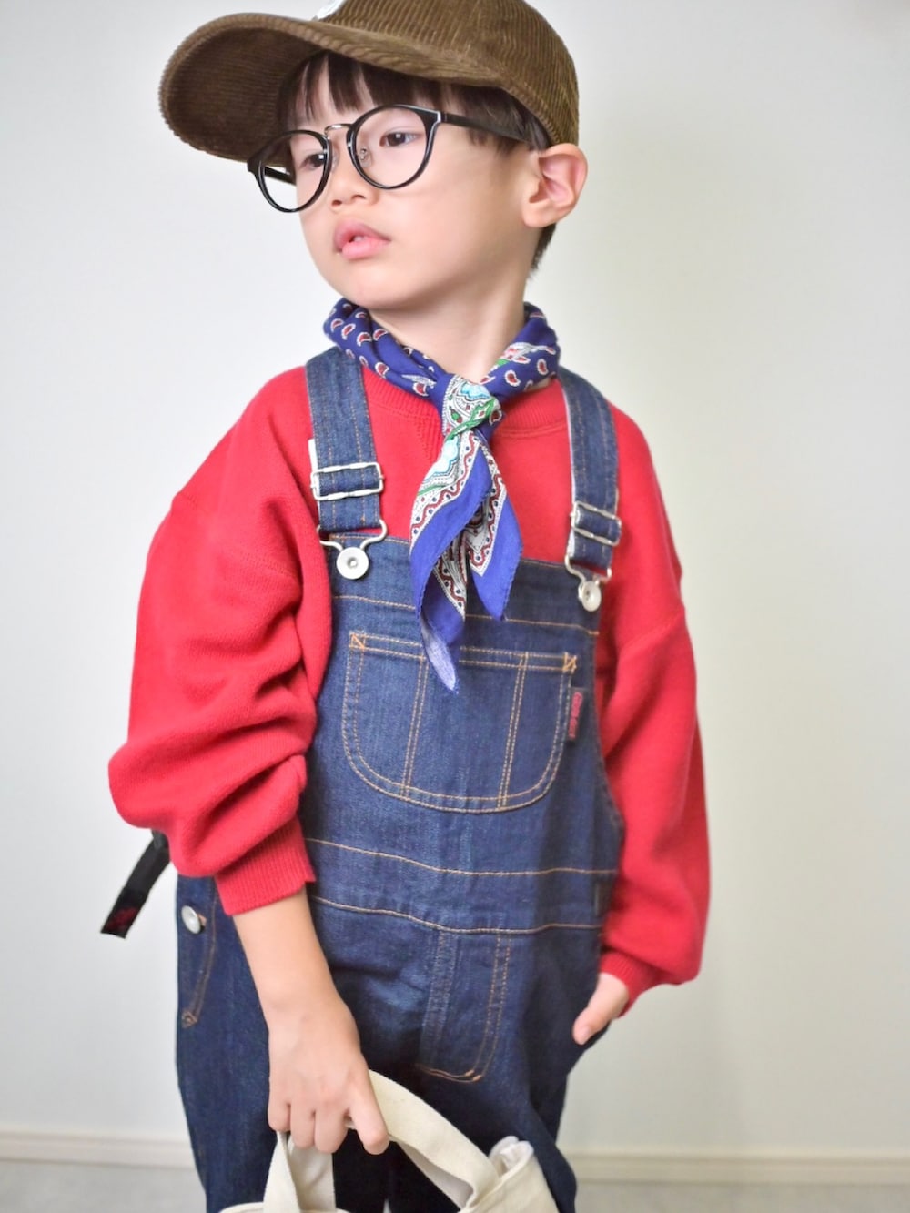 レッド系のニット/セーター、ブルー系のサロペット/オーバーオール、ブラック系のスニーカーを着用したキッズの秋コーディネートの5枚目の写真